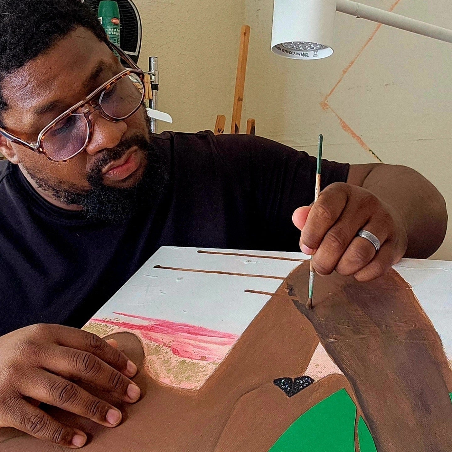 Keshida Layone painting at his studio table